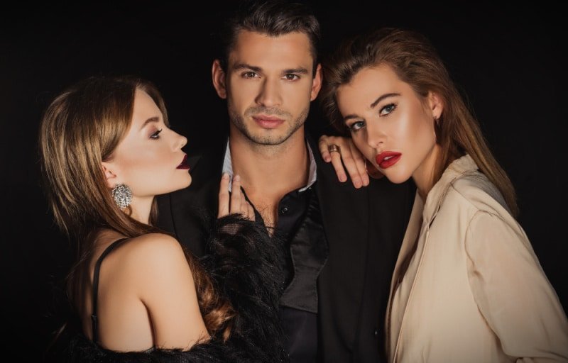 Attractive-man-with-two-beautiful-women-on-black-background